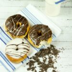 Indulgent chocolate donuts with milk presented on a rustic wooden table, perfect for dessert lovers.
