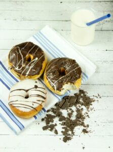 Indulgent chocolate donuts with milk presented on a rustic wooden table, perfect for dessert lovers.